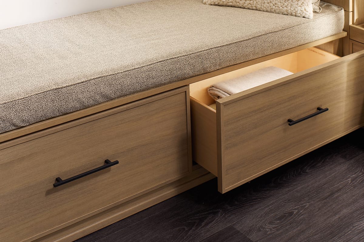 LED lighting in pull out drawers under a window bench in a walk in closet by California Closets