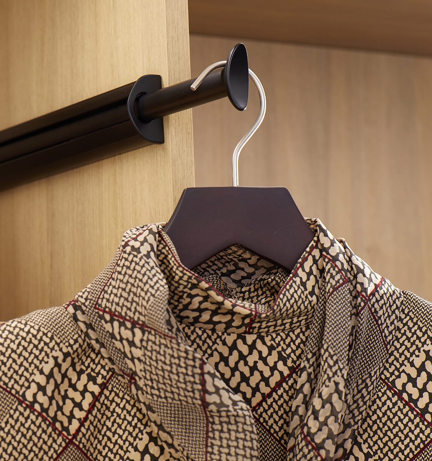 Customized wardrobe closet with light finish and valet rod by California Closets